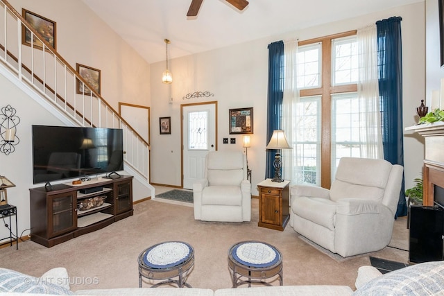 carpeted living room featuring stairs, ceiling fan, and high vaulted ceiling