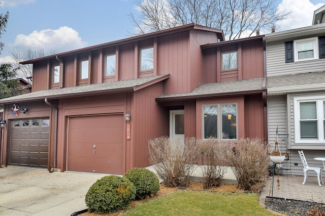 townhome / multi-family property featuring a garage, concrete driveway, and roof with shingles