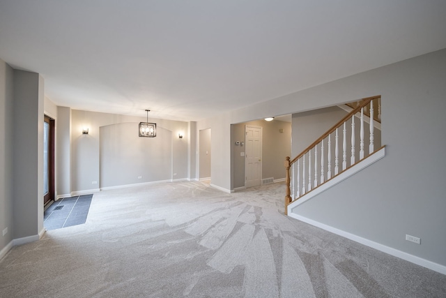 unfurnished room with light carpet, baseboards, stairway, and a notable chandelier