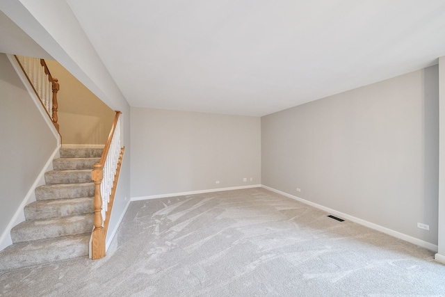 carpeted empty room with stairway, visible vents, and baseboards