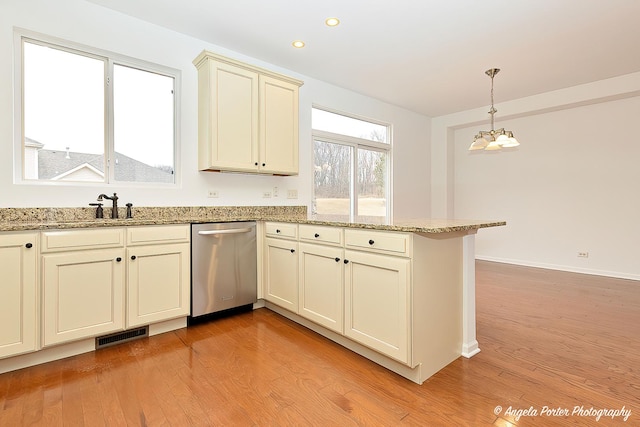 kitchen with a peninsula, light wood finished floors, a sink, and dishwasher