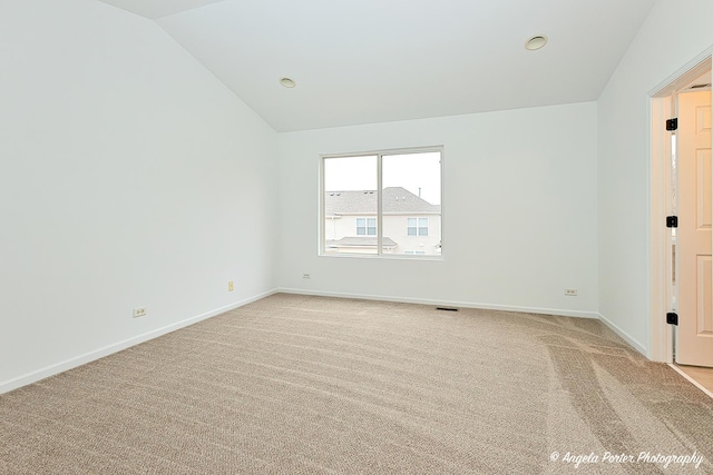 unfurnished room with vaulted ceiling, light colored carpet, and baseboards