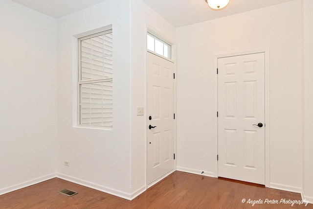 entrance foyer featuring baseboards, visible vents, and wood finished floors