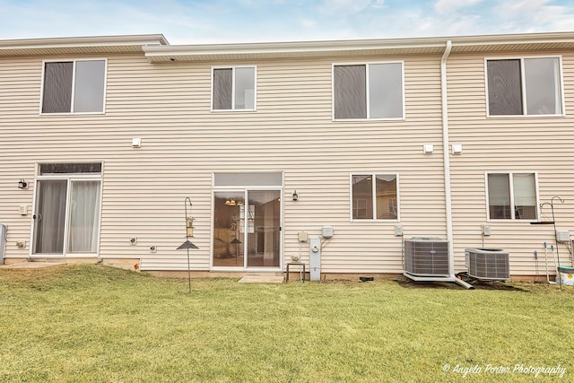 rear view of house featuring a lawn and central air condition unit