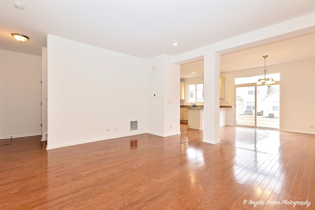 unfurnished living room with wood finished floors, visible vents, and baseboards