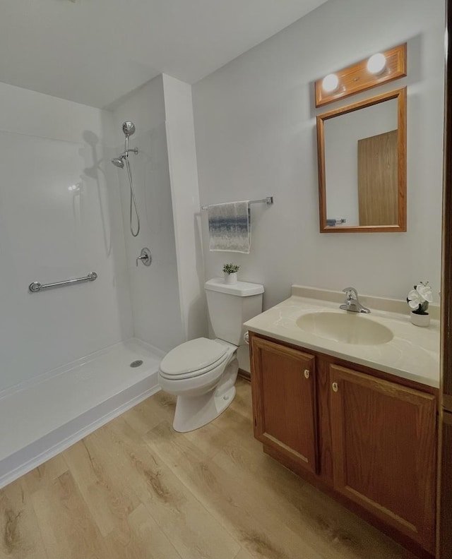 full bathroom featuring toilet, walk in shower, wood finished floors, and vanity