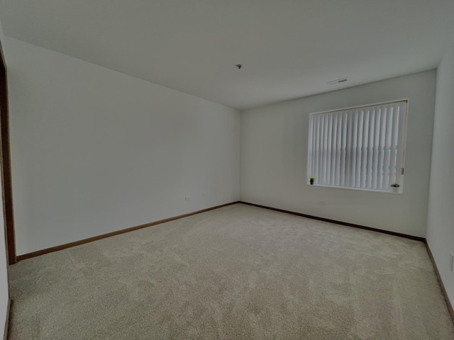 spare room with light carpet, visible vents, and baseboards