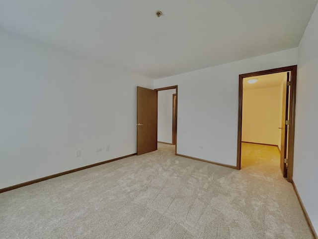 empty room featuring light carpet and baseboards