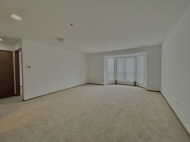 empty room with baseboards and light colored carpet