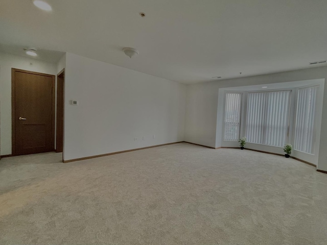 unfurnished room with light colored carpet, visible vents, and baseboards