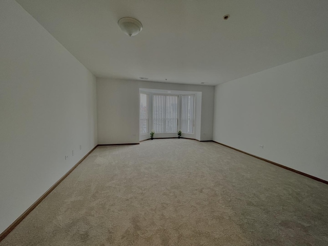 spare room with light carpet and baseboards