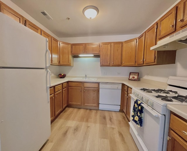 kitchen featuring white appliances, light wood finished floors, visible vents, under cabinet range hood, and a sink