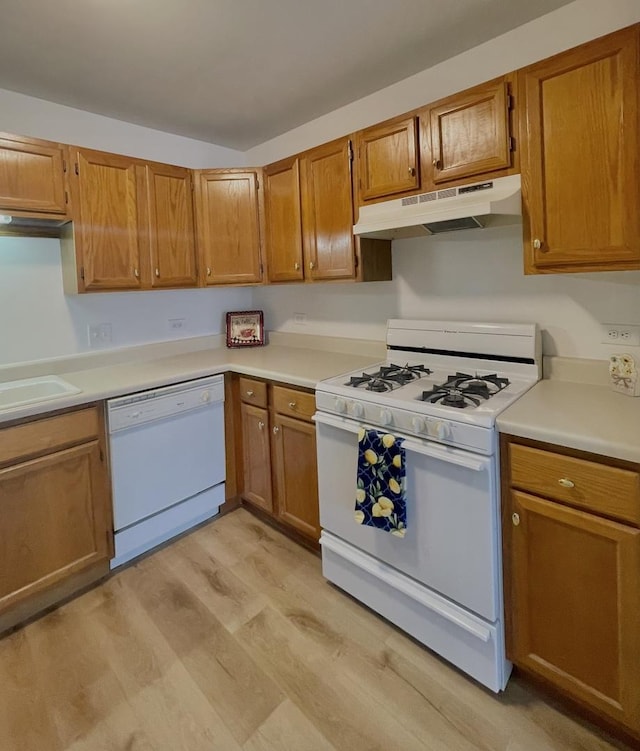 kitchen featuring light countertops, white appliances, light wood-style flooring, and under cabinet range hood