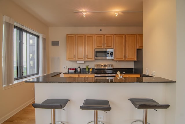 1322 S Prairie Ave Unit 1413, Chicago, IL 60605 - kitchen with stainless steel appliances, dark stone counters, a breakfast bar, light wood-type flooring, and a peninsula