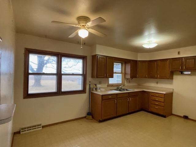 kitchen with light countertops, visible vents, a sink, and baseboards