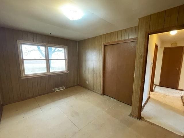 unfurnished bedroom featuring wood walls, visible vents, and a closet