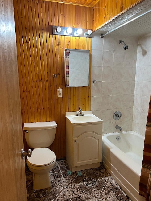 bathroom with tile patterned flooring, toilet, wooden walls, shower / tub combo, and vanity