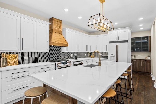 kitchen featuring a sink, high quality appliances, a kitchen breakfast bar, white cabinets, and custom range hood