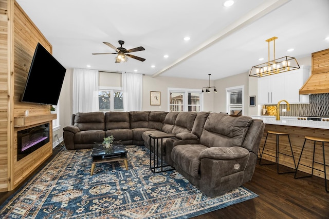 living area with recessed lighting, dark wood finished floors, a ceiling fan, and a glass covered fireplace