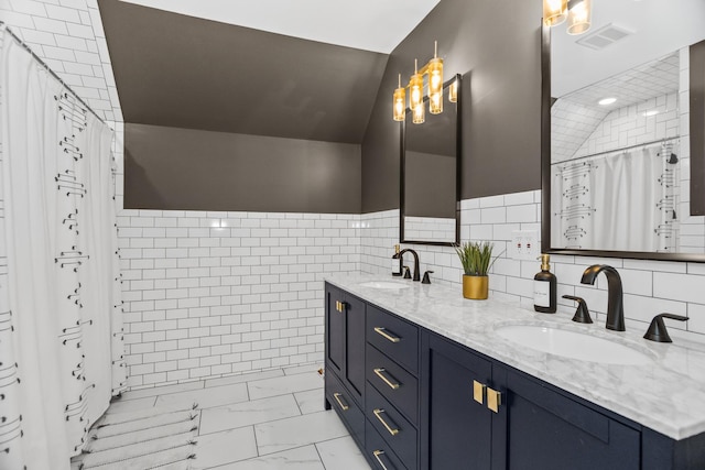 full bath featuring lofted ceiling, marble finish floor, and a sink