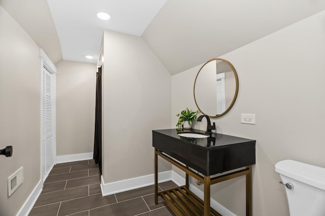 bathroom with toilet, recessed lighting, vanity, baseboards, and vaulted ceiling