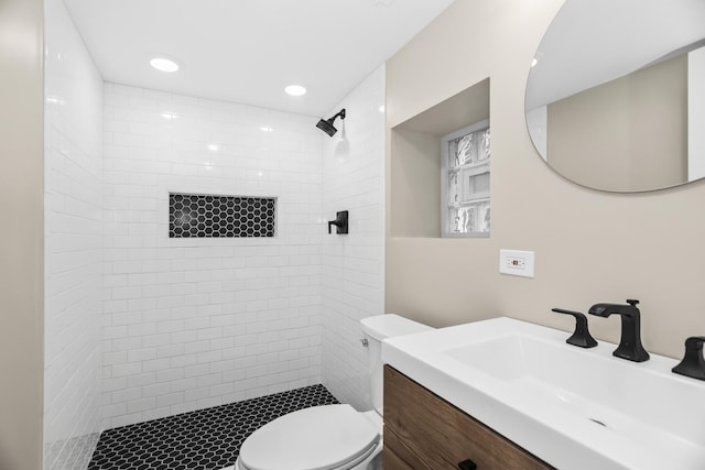 bathroom with toilet, recessed lighting, a tile shower, and vanity