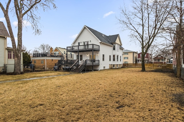 rear view of property featuring a deck, a lawn, and a fenced backyard