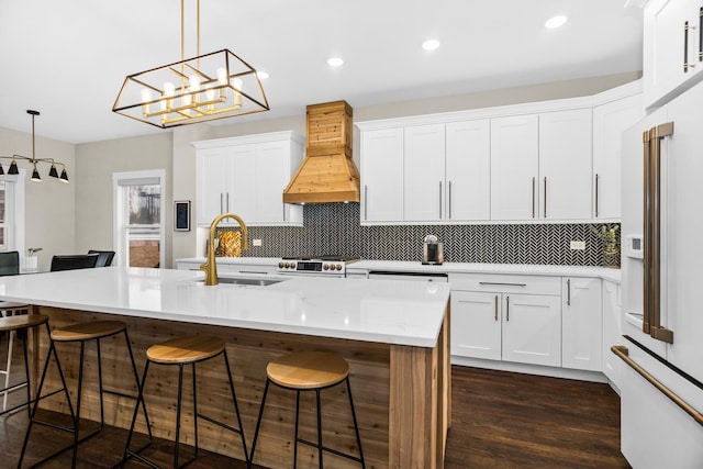 kitchen with a kitchen breakfast bar, high end white refrigerator, a sink, and custom range hood