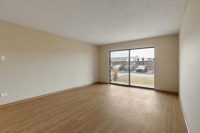 unfurnished room featuring light wood-style flooring, baseboards, and a textured ceiling