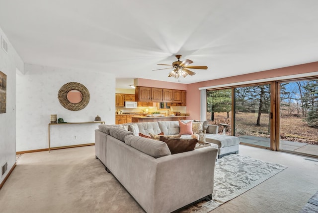 living room with wallpapered walls, visible vents, baseboards, light colored carpet, and ceiling fan