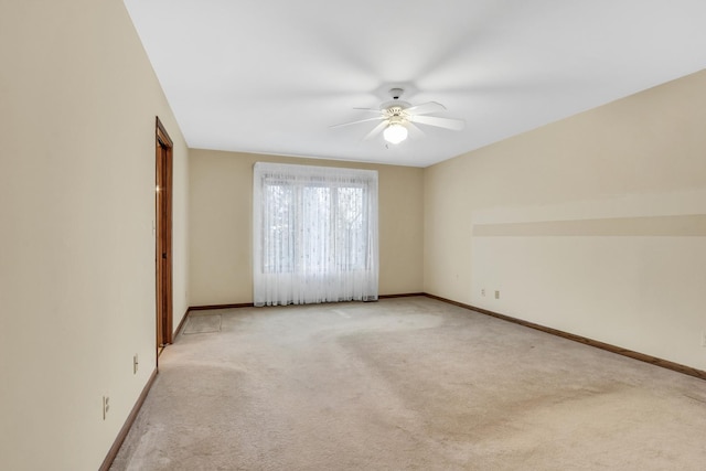 spare room featuring baseboards, ceiling fan, and light colored carpet