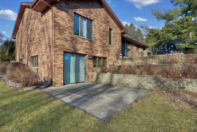 back of house with a patio area, brick siding, and a yard