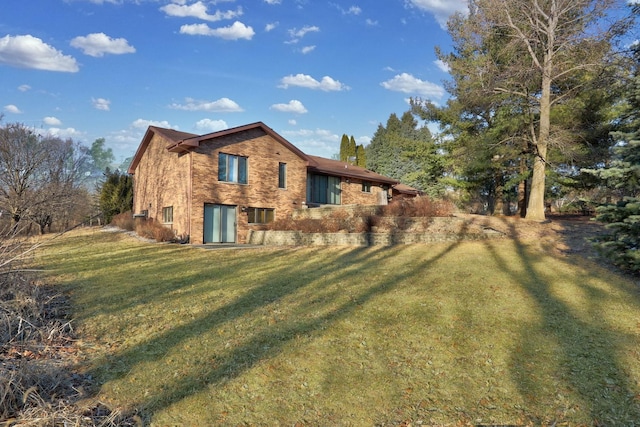 back of house featuring brick siding and a lawn