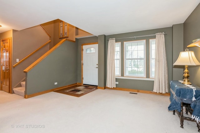 foyer featuring carpet, visible vents, stairway, and baseboards