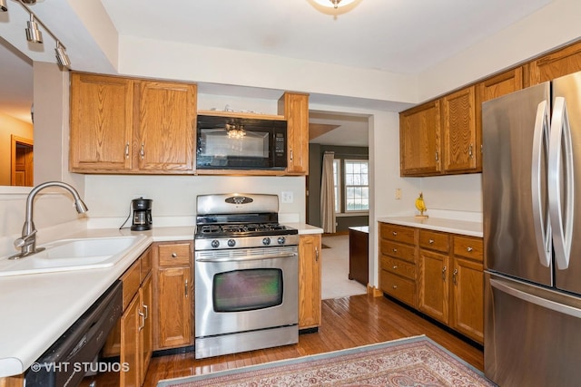 kitchen with black appliances, dark wood-style floors, light countertops, and a sink