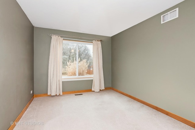 spare room featuring baseboards, visible vents, and light colored carpet