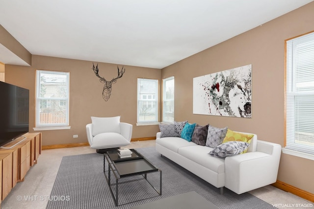 living area with light carpet, a wealth of natural light, and baseboards