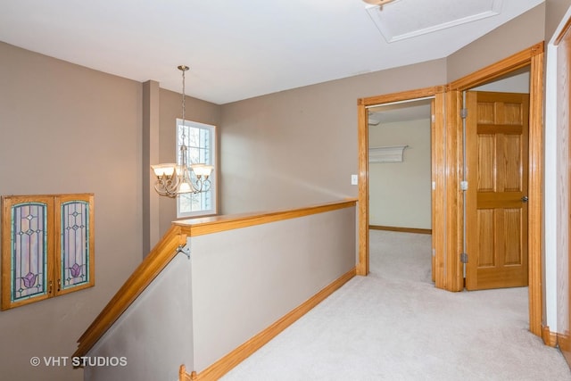 hallway featuring a chandelier, carpet, an upstairs landing, and baseboards