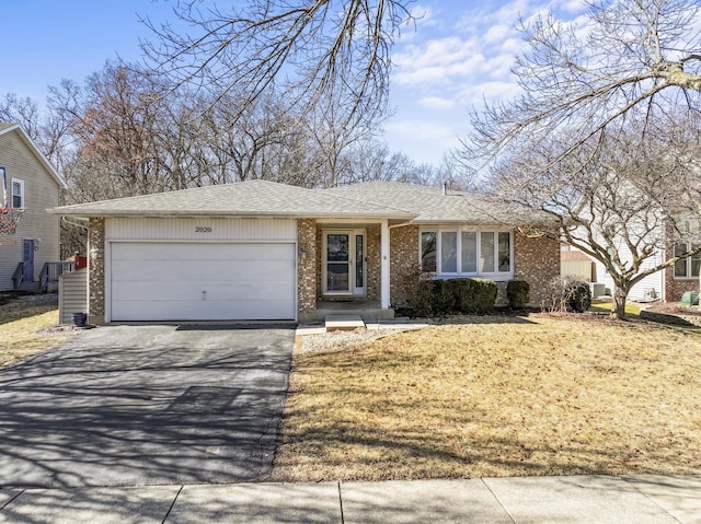 ranch-style home with driveway, an attached garage, roof with shingles, and brick siding