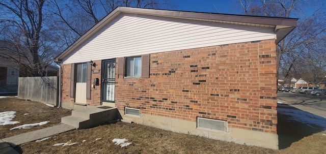 view of side of property featuring brick siding and fence