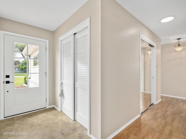 entrance foyer with a chandelier, light wood-style floors, and baseboards