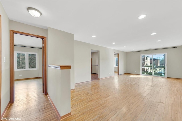 empty room featuring recessed lighting, light wood-type flooring, and baseboards