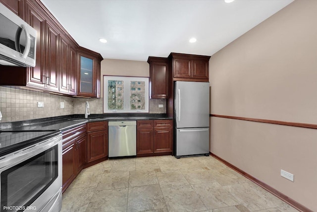 kitchen featuring dark countertops, backsplash, appliances with stainless steel finishes, and a sink