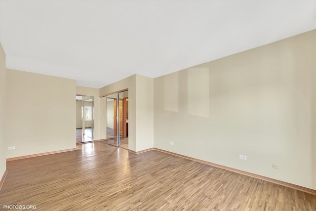 spare room featuring baseboards and light wood-style floors