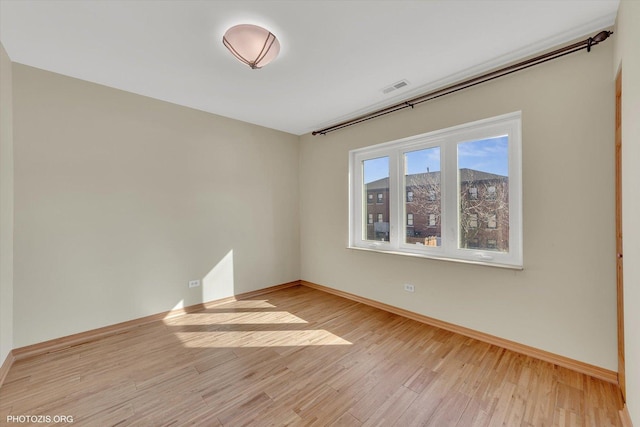 unfurnished room with baseboards, visible vents, and light wood finished floors