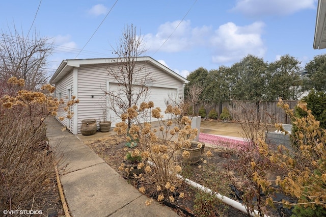 view of home's exterior featuring an outbuilding, a detached garage, and fence