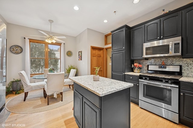 kitchen with tasteful backsplash, appliances with stainless steel finishes, light wood-type flooring, and a center island