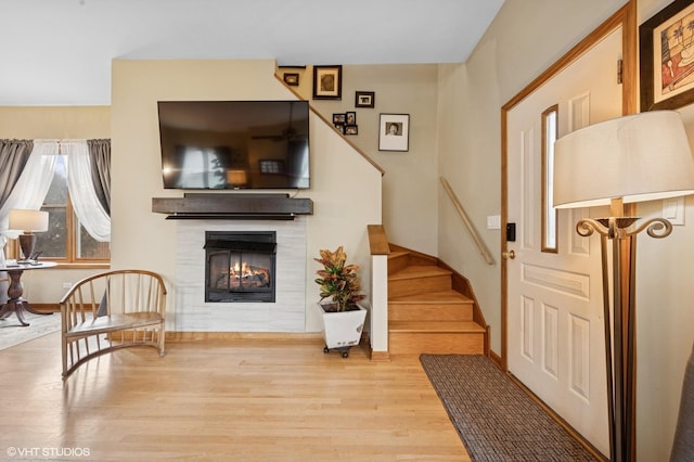 interior space featuring a warm lit fireplace, stairway, and wood finished floors