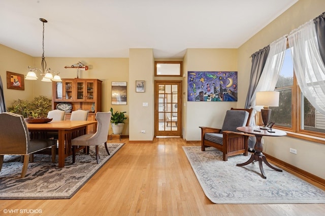 dining room with light wood-type flooring, an inviting chandelier, and a wealth of natural light