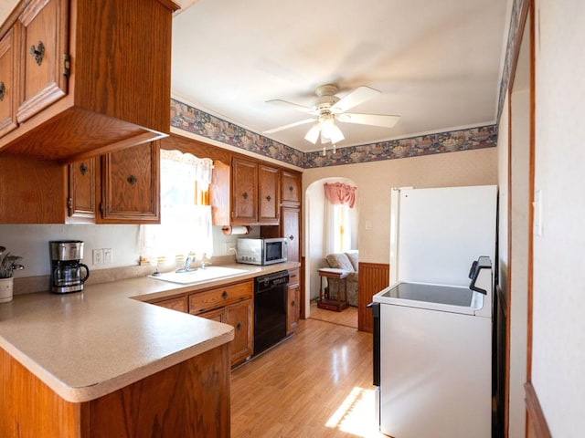 kitchen with arched walkways, freestanding refrigerator, a sink, black dishwasher, and stainless steel microwave